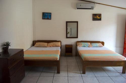 a bedroom with two beds and a dresser and a mirror at Hotel Sol Puntarenas in Puntarenas