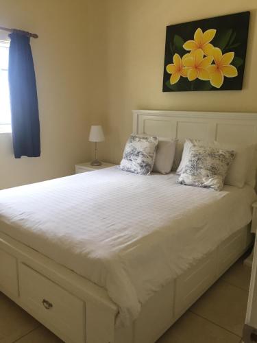 a bedroom with a white bed with two pillows at South Sea House in Cap Estate