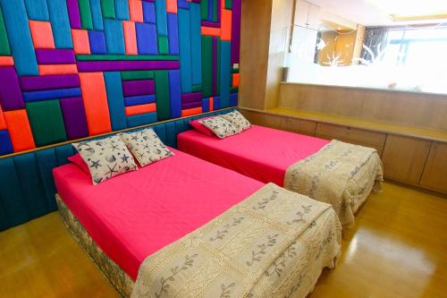 two beds in a room with a colorful wall at Cha am Beach Club in Phetchaburi