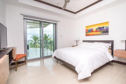 a white bedroom with a bed and a large window at Best in Jaco Condos at Diamante del Sol in Jacó