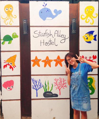 a young girl standing in front of a wall with animals at Starfish Alley Hostel in Da Nang