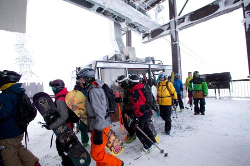 a group of people standing in the snow with snowboards at Higashikawa Asahidake Onsen Hotel Bear Monte in Higashikawa