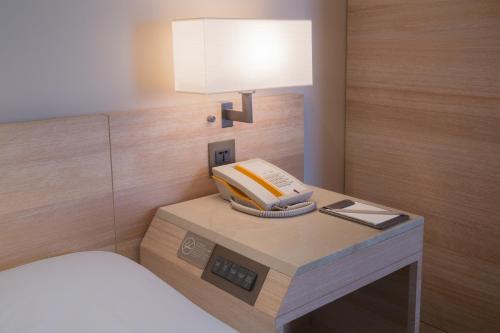 a bed room with a phone and a lamp on a table at Hotel COZZI Minsheng Taipei in Taipei