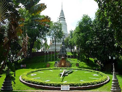 a large clock in a park with a building in the background at Orussey One Hotel & Apartment in Phnom Penh