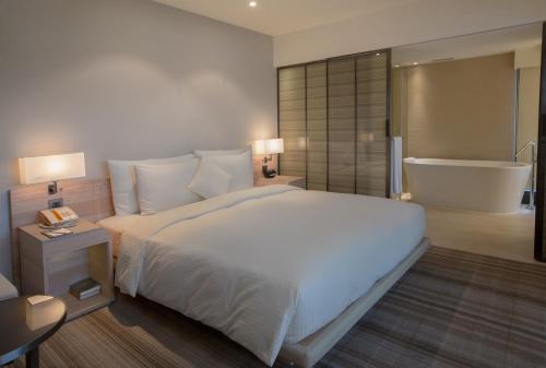 a bedroom with a large bed and a bath tub at Hotel COZZI Minsheng Taipei in Taipei