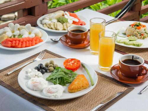 einen Tisch mit Teller mit Lebensmitteln und Tassen Orangensaft in der Unterkunft Boujis Boutique Resort in Strand Chaweng Noi