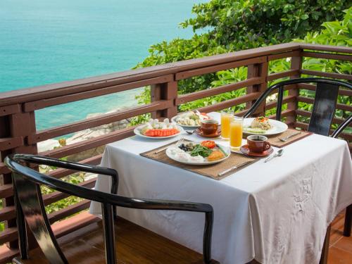 einen Tisch mit Teller mit Speisen auf einem Balkon mit Meerblick in der Unterkunft Boujis Boutique Resort in Strand Chaweng Noi