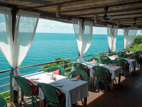 ein Restaurant mit Tischen und Stühlen und dem Meer in der Unterkunft Boujis Boutique Resort in Strand Chaweng Noi