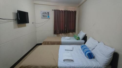 a small room with two beds and a television at Calamba Pension Plaza in Calamba