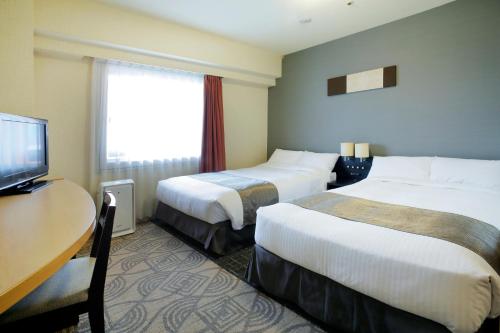 a hotel room with two beds and a desk and a television at Sapporo Tokyu REI Hotel in Sapporo