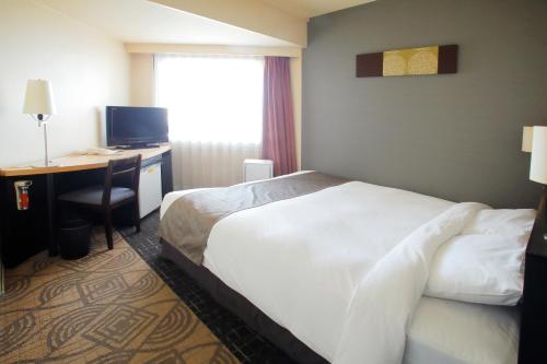 a hotel room with a bed and a desk with a computer at Sapporo Tokyu REI Hotel in Sapporo