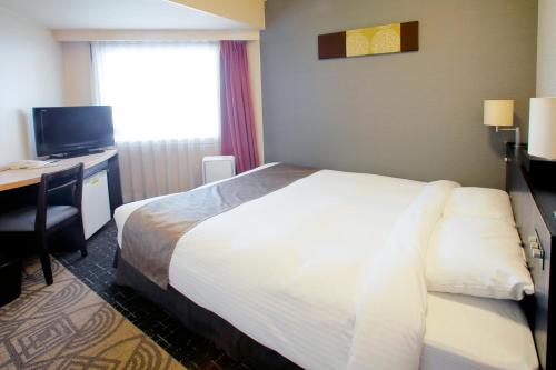 a hotel room with a bed and a desk with a computer at Sapporo Tokyu REI Hotel in Sapporo