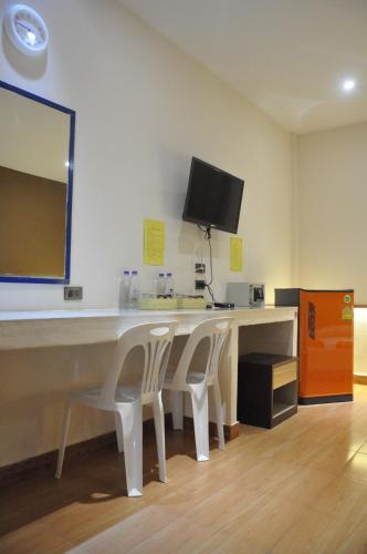 a room with a desk with two chairs and a television at Banana Resort Sadao in Sadao