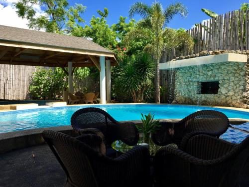 una piscina con sillas y una mesa junto a ella en Lapu-Lapu Cottages & Restaurant, en Mactan