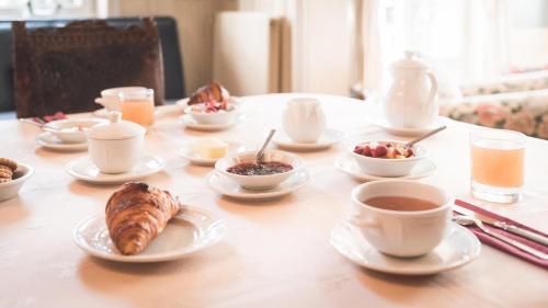 a table with plates of food and cups of coffee at Manoir de Sens in Beuvron-en-Auge