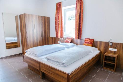 a bedroom with a large wooden bed with white sheets at Haus Bachforelle in Millstatt