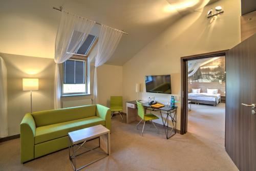 a living room with a green couch and a table at Hotel Loft 1898 in Suwałki