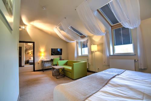 a bedroom with a bed and a couch and windows at Hotel Loft 1898 in Suwałki