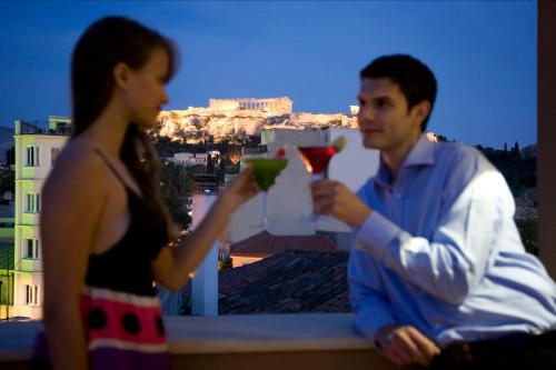 een man en een vrouw met een drankje op een balkon bij O&B Athens Boutique Hotel in Athene