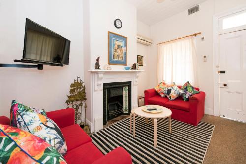 a living room with two red couches and a fireplace at Ningana Heritage Houses in Mudgee