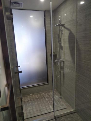 a shower with a glass door in a bathroom at INSAIL Hotel (Shenzhen Dongmen Branch) in Shenzhen