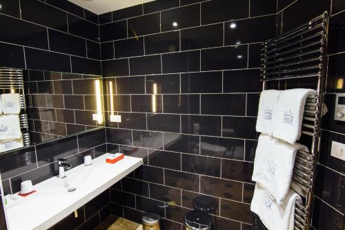 La salle de bains est pourvue de carrelage noir, d'un lavabo et d'un miroir. dans l'établissement Château D'igé, à Igé