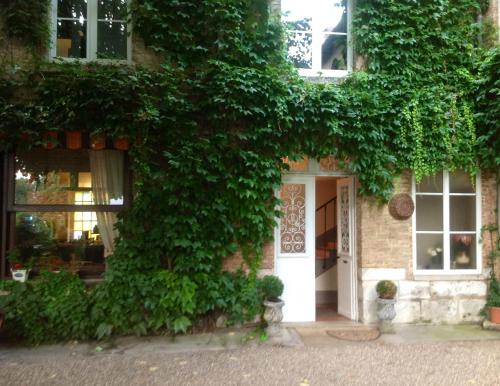 um edifício coberto de hera com uma porta branca em Chambres D'Hôtes La Villa Aliénor em Les Andelys