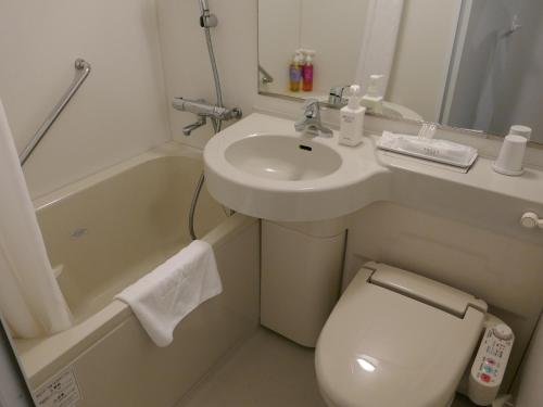 a small bathroom with a sink and a toilet and a sink at Sotetsu Fresa Inn Ginza Sanchome in Tokyo