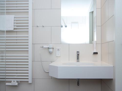Baño blanco con lavabo y espejo en Seligweiler Hotel & Restaurant, en Ulm