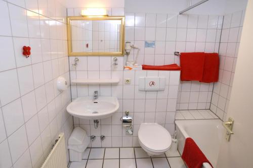 a white bathroom with a sink and a toilet at Apart Hotel Sehnde in Sehnde
