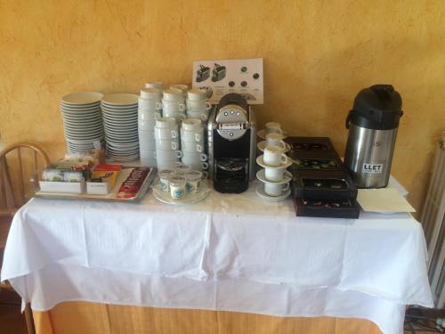 einen Tisch mit Tassen und Tellern sowie eine Kaffeemaschine in der Unterkunft Hotel Mirador in Lles