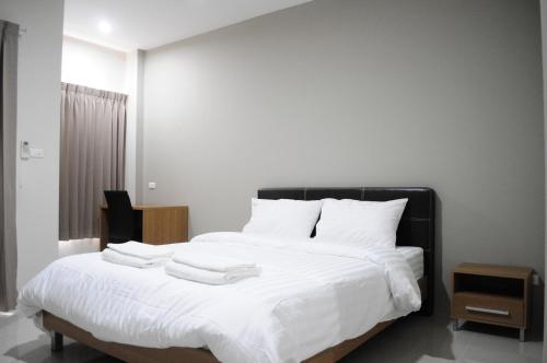 een slaapkamer met een wit bed en 2 handdoeken bij Paru Ville in Nakhon Ratchasima