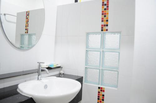 een witte badkamer met een wastafel en een spiegel bij Paru Ville in Nakhon Ratchasima