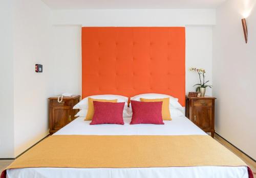 a bedroom with a white bed with red and yellow pillows at Don Antonino Relais in Sorrento