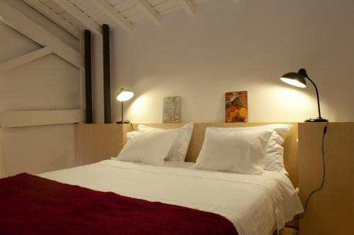 a bedroom with a bed with white sheets and pillows at Coimbra Vintage Lofts Apartments in Coimbra