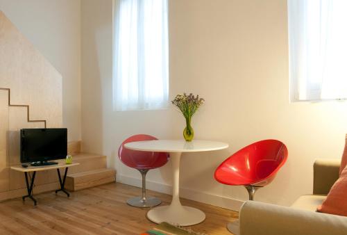 a living room with a table and two red chairs at Coimbra Vintage Lofts Apartments in Coimbra