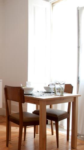 a wooden table with two chairs and a table with glasses on it at Coimbra Vintage Lofts Apartments in Coimbra