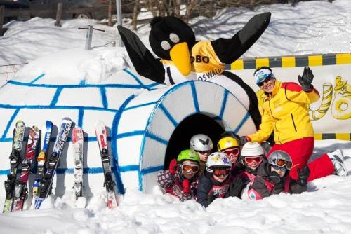 a group of people in the snow in front of a penguin tunnel at Ferienwohnung Brennseeblick in Feld am See