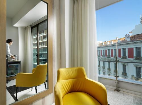 a yellow chair in a room with a window at Athens Tiare by Mage Hotels in Athens