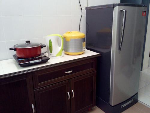 a kitchen counter with a refrigerator and a pot and pans at Az Zahra Homestay KLIA Sepang in Sepang