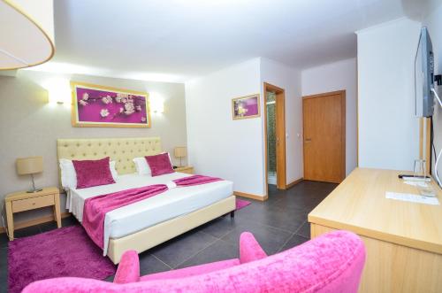 a bedroom with a bed and two pink chairs at Vivi Hotel in Praia