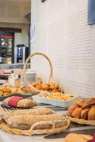 una mesa con diferentes tipos de panes y bollería en Hôtel & Spa du Domaine des Thômeaux, The Originals Relais, en Mosnes