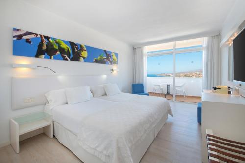 Dormitorio blanco con cama grande y vistas al océano en Iberostar Waves Bouganville Playa, en Adeje