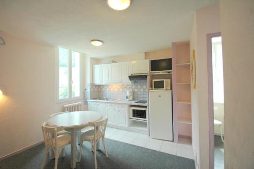 a kitchen with a table and a white refrigerator at Appart Le Chili- Quartier thermal- Parc remarquable - Linge fourni in Luz-Saint-Sauveur
