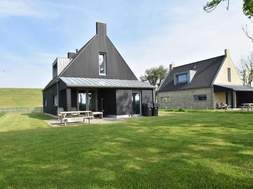 una casa con techo negro y patio de césped en Detached villa on the Zeedijk with view, en Tzummarum
