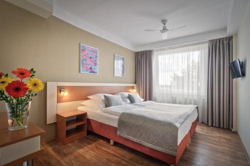 ein Hotelzimmer mit einem Bett und einer Vase aus Blumen in der Unterkunft Hotel Aida in Prag