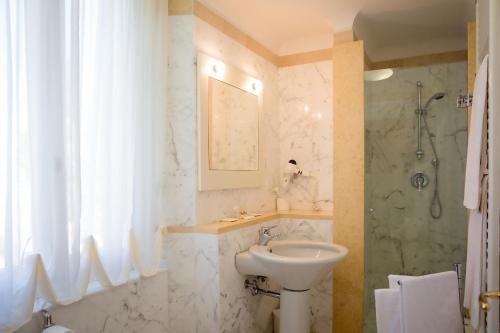 a white bathroom with a sink and a shower at Palazzo La Fenice in Massa Marittima
