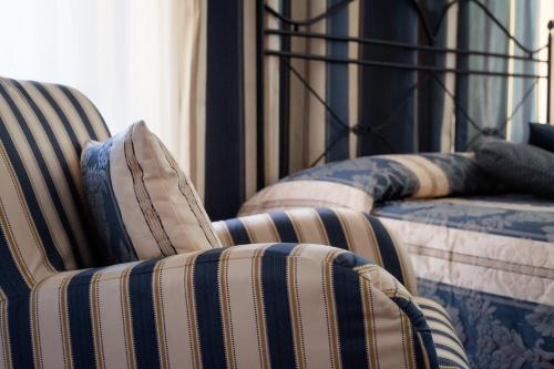 two beds with striped chairs in a bedroom at Dimora Palazzo La Fenice in Massa Marittima
