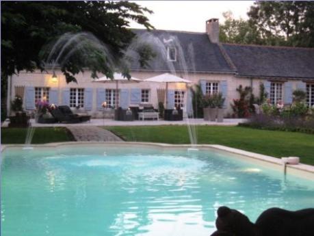a swimming pool with a fountain in front of a house at Le Mouton in Blaison