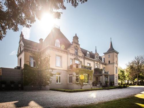 a large white house with the sun in the sky at Landgoed Kasteel de Hoogenweerth in Maastricht